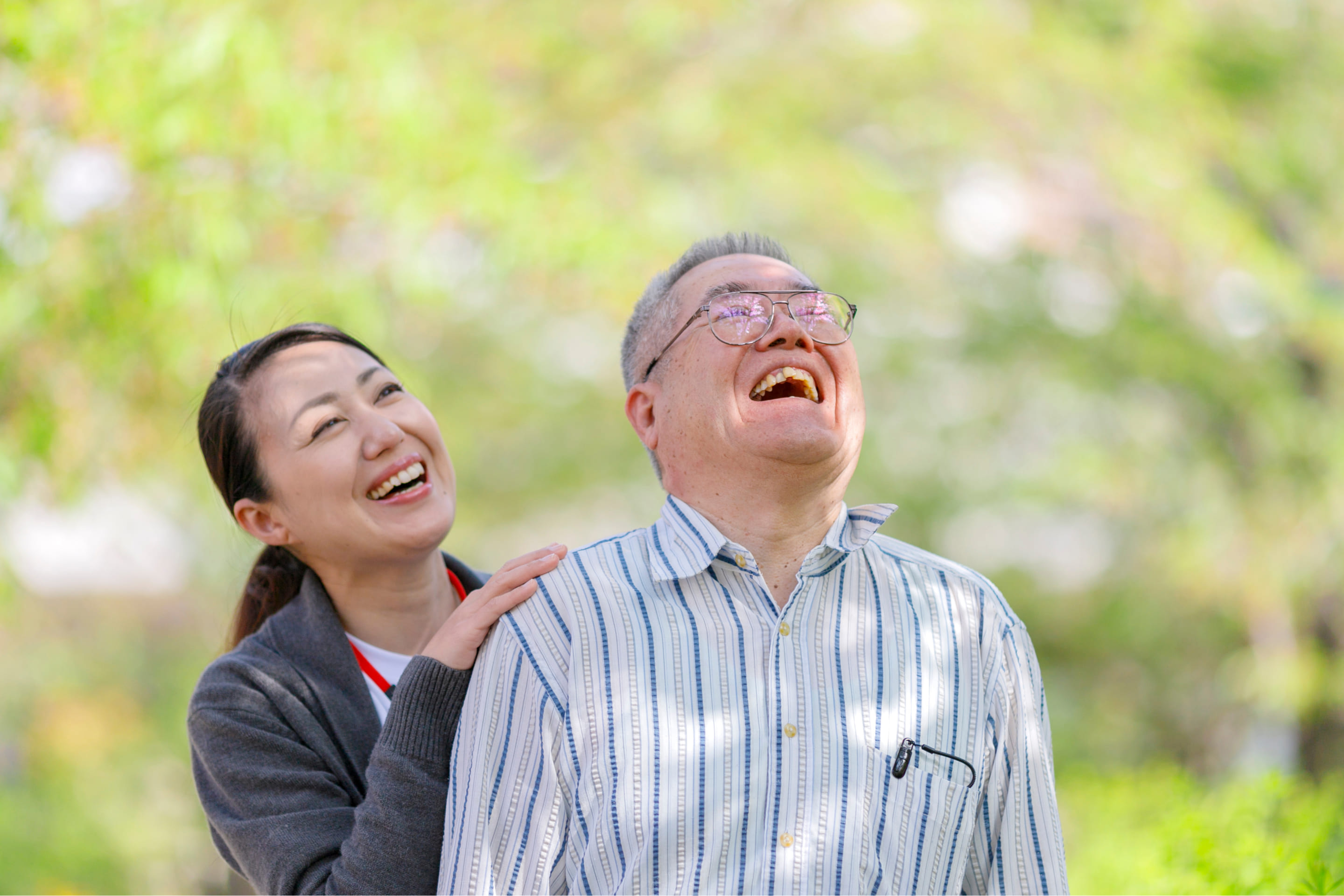 介護士と車椅子に乗った男性が空を見上げ笑っている様子
