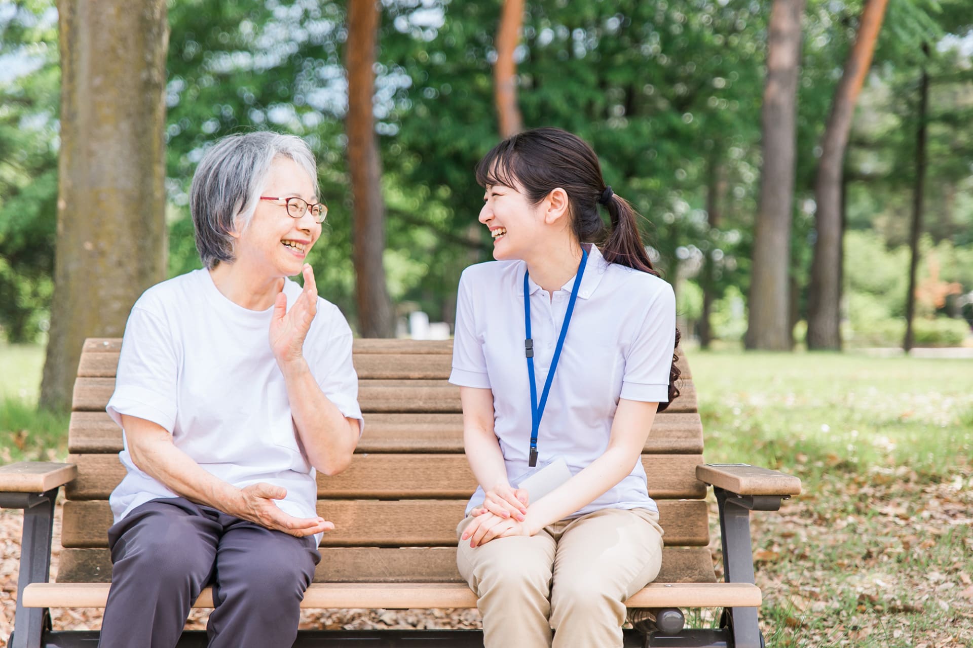 女性とケアマネージャーがベンチに座り笑顔で話している様子